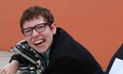 Beth Moulam and lifelong learning. Woman in wheelchair, hugging communication aid, AAC