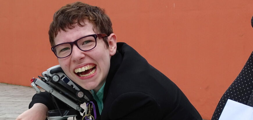 Beth Moulam and lifelong learning. Woman in wheelchair, hugging communication aid, AAC