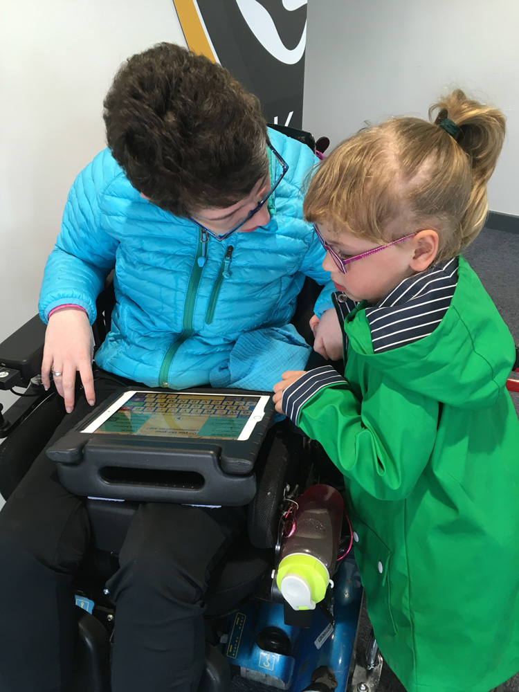 Beth Moulam using communication aid with young girl