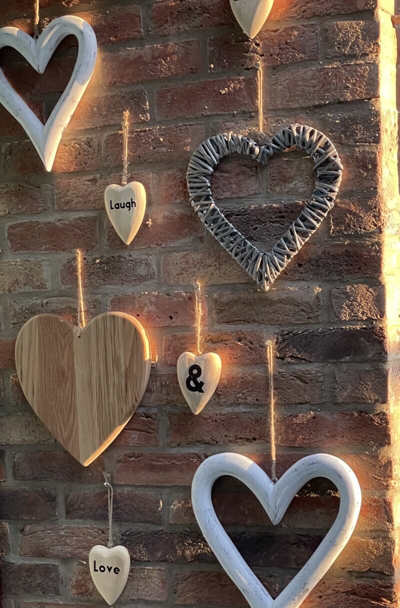 various hearts displayed on brick wall caught in sunlight by Beth Moulam