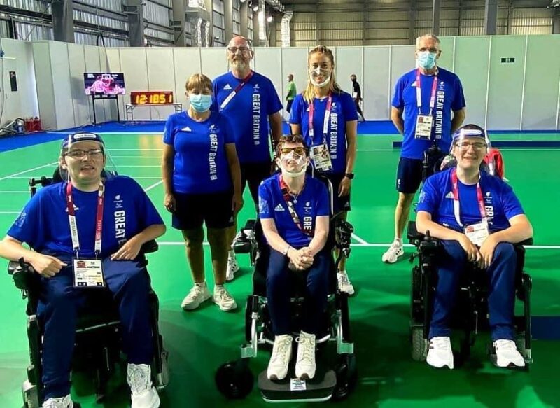 Beth Moulam Boccia BC3 athlete sat front and centre with her BC3 team mates, their 3 sports assistants and coach in Ariake Stadium in Tokyo at the 2020 Paralympics. All wearing Great Britain blue shirts.