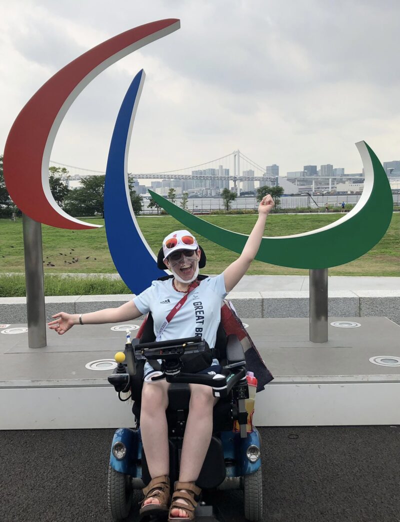 Beth Moulam, female Paralympian sat in front of the agitos logo in Tokyo
