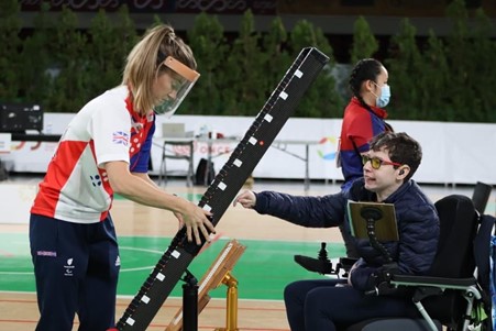 Beth Moulam BC3 boccia athlete with Christie Hutchings ramp operator at the BISFed European Championships 2021. Beth is wearing a blue jacket and Christe GB kit and a clear face mask for lip reading.