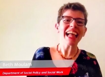 Beth Moulam, woman wearing black flowered blouse, amber beads and glasses. Student Orator at University of York graduation