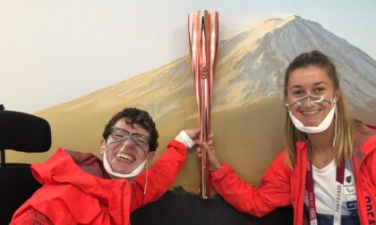 Two women, Beth Moulam and Christie Hutchings wearing red jackets holding the Paralympic Torch in Tokyo 2021