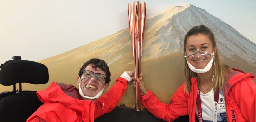 Two women, Beth Moulam and Christie Hutchings wearing red jackets holding the Paralympic Torch in Tokyo 2021