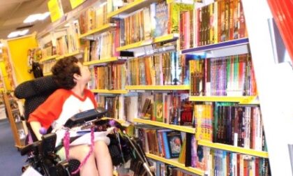 Beth Moulam, girl in red and white t shirt, looking at books sat in wheelchair, world book day