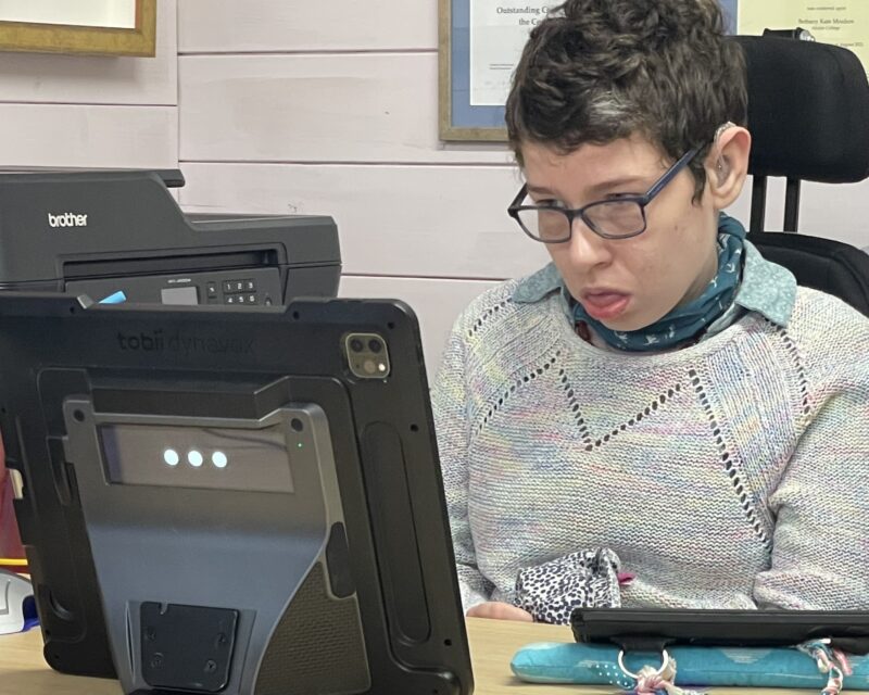 Beth Moulam woman wearing glasses and hearing aids trying out the TD Pilot (concentrating hard)