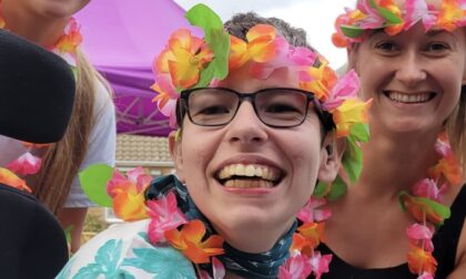 Beth Moulam and support team. AAC user and self advocate, Woman wearing glasses and flower headband and neck garland.