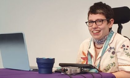 Beth Moulam Keynote speaker. Sat at a podium with her AAC equipment
